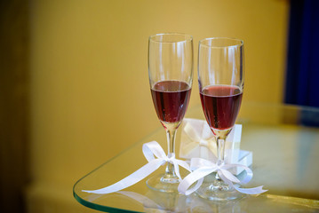 Two glasses of Pink Champagne one with a wedding ring inside and hearts in the air. with room for your text or images