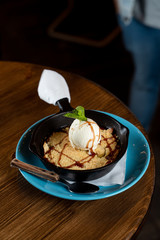 Traditional english crumble cake with apples and scoop of vanilla ice cream served in cast iron baking pan