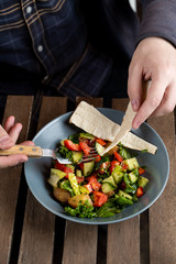 Young man is having a light meal with warm seasonal salad with baked jacket potato, served with flat bread