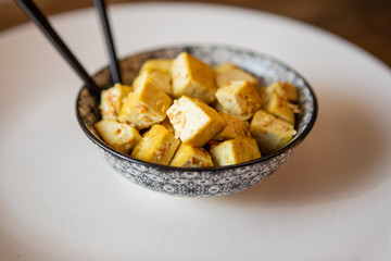 stir fry tofu with curry and sesame seeds into an oriental bowl and chopsticks