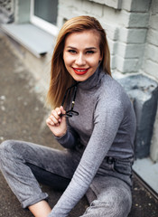 Close up fashion street stile portrait of young stylish girl student wearing boyfriend jeans, white sneakers and gray jeans.Pretty laughing girl has a good time in autumn weekend