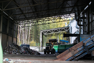 Fototapeta na wymiar Modern plant for processing and sorting of municipal urban waste - evening sunlight in huge reception junkyard room, hangar for unloading waste from trucks and further processing sorting and reuse.