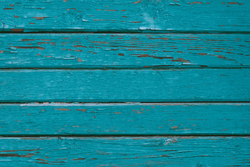 Turquoise painted fence, dilapidated cracked boards, green wooden fence. Rustic timber texture. Weathered oak planks. Natural background, pattern. Peeling paint on old wood table.