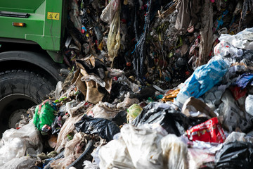 Truck tipping garbage from container on junk yard