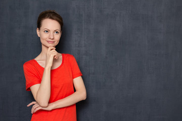 Portrait of focused dreamy woman touching chin with one hand