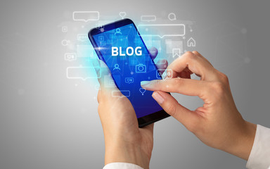 Female hand typing on smartphone with BLOG inscription, social media concept