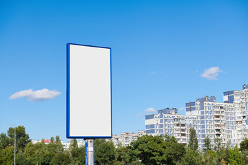 Big vertical billboard with copy space on urban background against blue sky. Advertising space with...