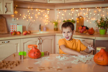 7 happy cute baby sitting at a table in the kitchen waiting for Halloween and preparing a gingerbread cookie