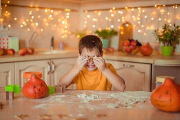 7 happy cute baby sitting at the table waiting for the Halloween holiday and holding gingerbread cookies in the shape of stars, closing their eyes