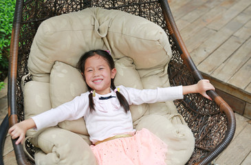 Smiling Asian little child girl lying on sofa in the garden.