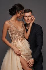 Portrait of a sexy woman in evening luxury dress seducing her handsome lover in black suit.