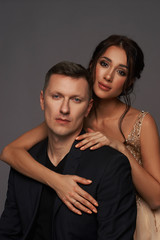 Closeup studio fashion portrait of elegant stylish young adult couple. Caucasian brunette woman with hairstyle.