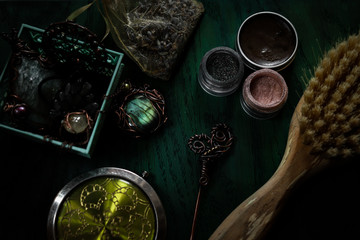 Copper jewelry, natural comb, hairpin, eyeshadows, perfume and pocket mirror on a dark wooden background