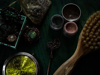 Copper jewelry, natural comb, hairpin, eyeshadows, perfume and pocket mirror on a dark wooden background