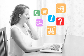 Woman sitting at the table in front of a laptop and talking on the phone.