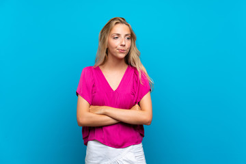 Obraz na płótnie Canvas Blonde young woman over isolated blue background with confuse face expression