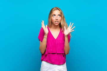 Blonde young woman over isolated blue background frustrated by a bad situation