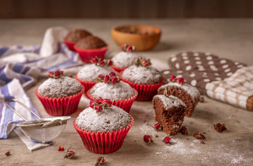 Chocolate muffins with powdered sugar and decor of dried tea roses.
