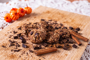 Chocolate cookies on wooden table with cinnamon sticks. Autumn style food photo with pumpkin.