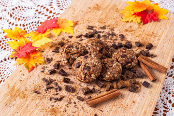 Chocolate cookies on wooden table with cinnamon sticks. Autumn style food photo with leaves.