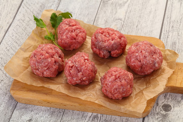 Raw meatball over wooden background