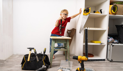 A boy works in a hand drill and repairs furniture