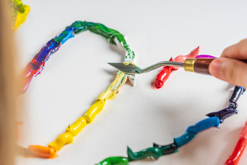 Bright squeezed oil paints on canvas. Girl draws with a palette knife. The process of creating a picture.