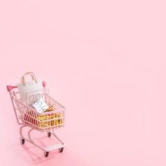 Annual sale shopping season concept - mini red shop cart trolley full of paper bag gift isolated on pale pink background, blank copy space, close up