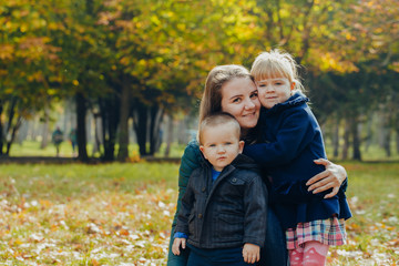 Beautiful young mother with daughter and son are walking in the autumn park. close-up portrait