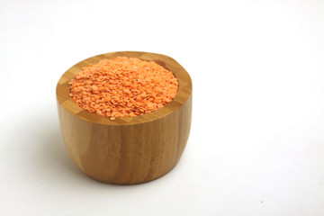 wooden bowl of red lentils isolated on white background. Image contains copy space