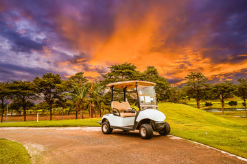 A golf cart parking on road at golf course with beautiful twilight sky background, summer color...