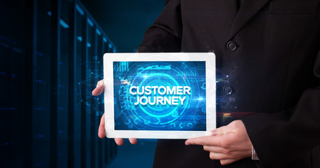 Young business person working on tablet and shows the inscription: CUSTOMER JOURNEY, business concept