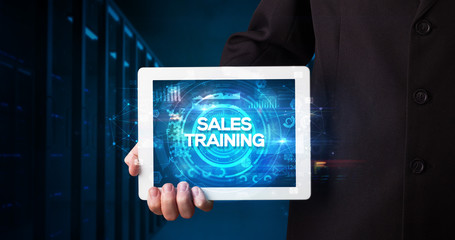 Young business person working on tablet and shows the inscription: SALES TRAINING, business concept