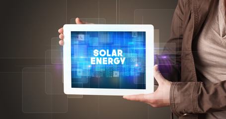 Young business person working on tablet and shows the inscription: SOLAR ENERGY