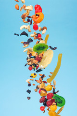 Dried and candied fruits and nuts flying on blue background. Stock photo of healty and nutrient food.