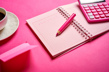 Closeup of calculator and notebook with pencil on pink desk