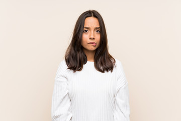 Young brunette woman with white sweater over isolated background having doubts and with confuse face expression