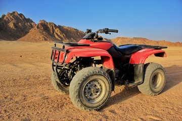 Red ATV in the desert with mountains view 