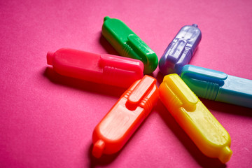 Close up of colorful markers on intense blurred pink background