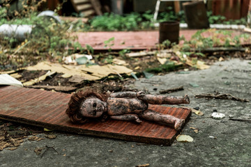 selective focus of burnt baby doll on asphalt in chernobyl