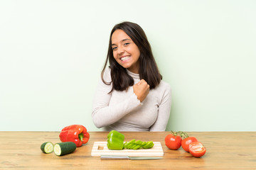 Young brunette woman with vegetables celebrating a victory