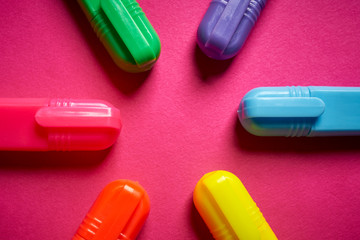 Close up of colorful markers on intense blurred pink background