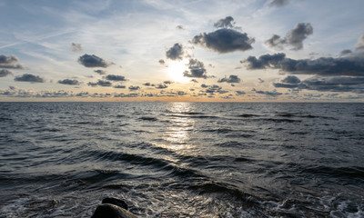 seascape image of the sea with cloudy sky before sunset,  stones and  of light before sunset, beautiful sunny day and quiet sea. baltic sea, Tuja beatch, Latvia