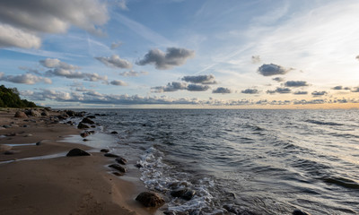 seascape image of the sea with cloudy sky before sunset,  stones and  of light before sunset, beautiful sunny day and quiet sea. baltic sea, Tuja beatch, Latvia