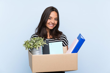 Young brunette girl making a move while picking up a box full of things smiling a lot
