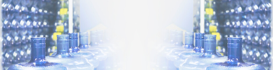 Blue water plastic bottles on conveyor. Closeup. Potable bottled water production. Wide panoramic image. Foggy fading background. Copy space.