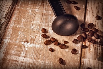 Measuring spoon for coffee maker and coffee beans on wooden background