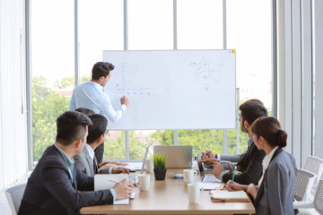 businessman coaching in team meeting or training, speaker drawing graph on white board (business seminar concept)