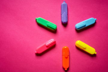 Close up of colorful markers on intense blurred pink background