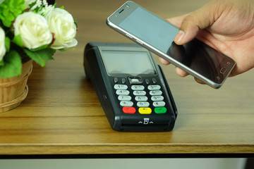 Hand of business man is holding smartphone and POS Terminal Credit Card Machine, wireless payment